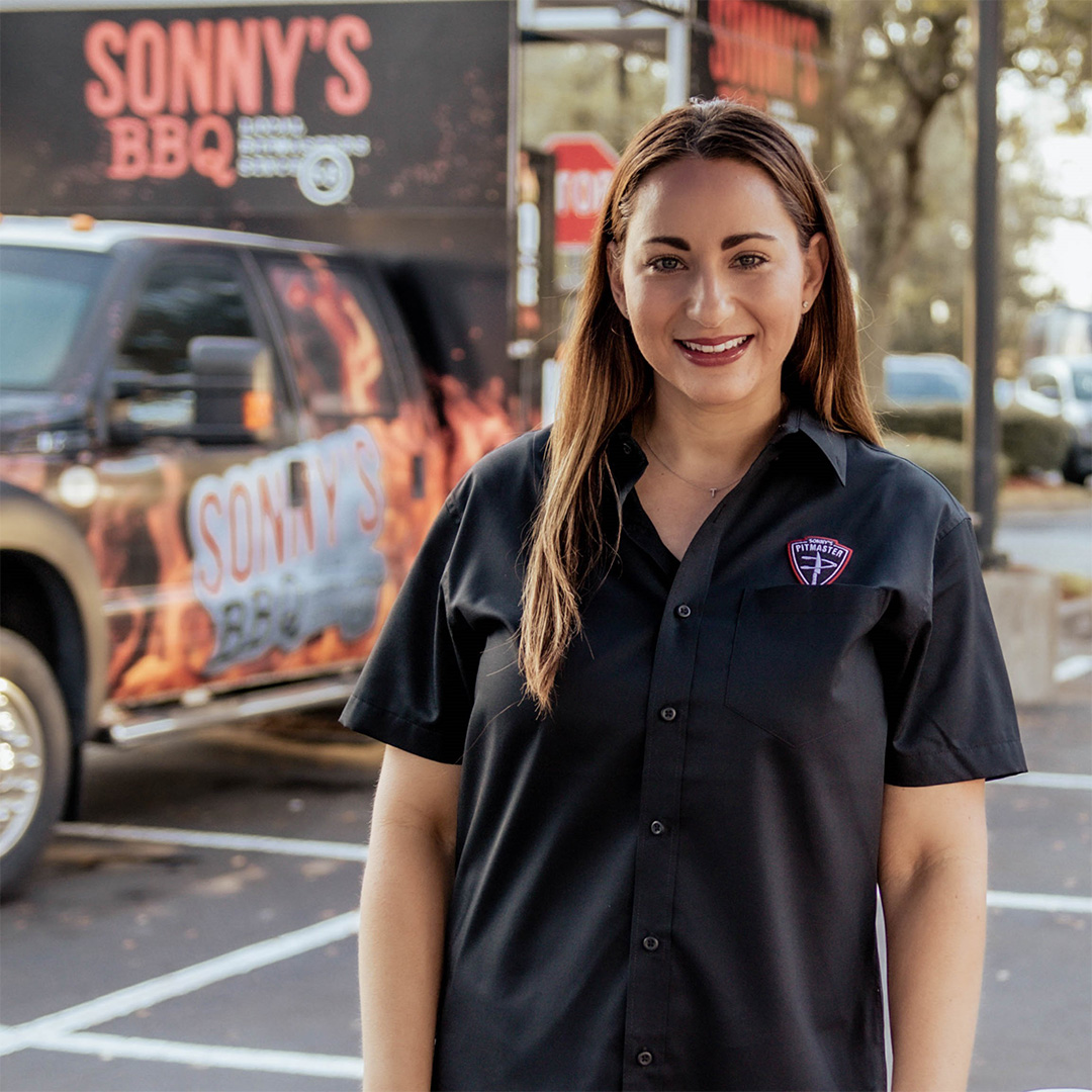 Chief Kindness Officer Tara Boyle poses for a picture in her Sonny's Pitmaster shirt