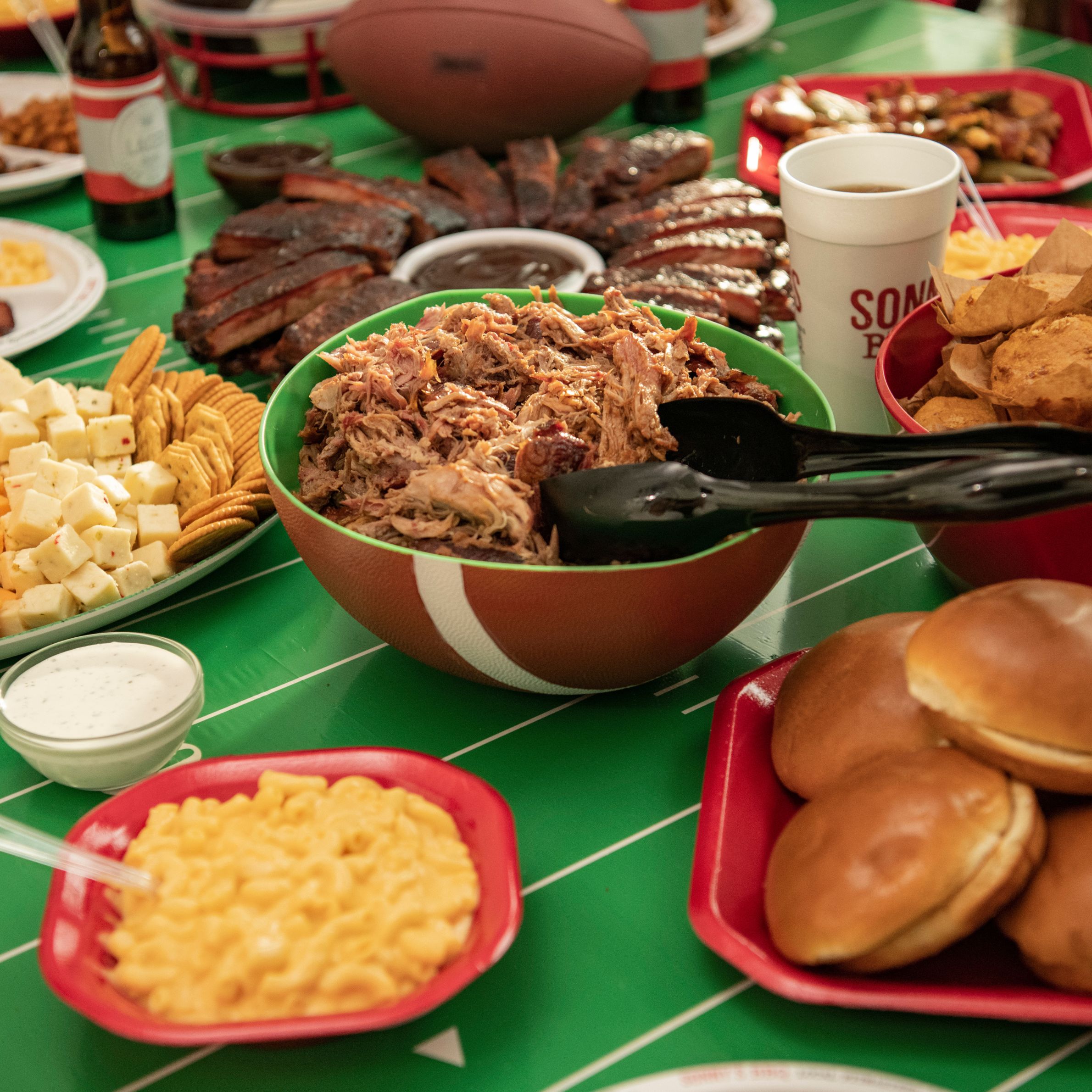 Catering spread of Pulled Pork, Mac & Cheese, Crackers, Buns, Cornbread, Ribs and more at a Tailgate